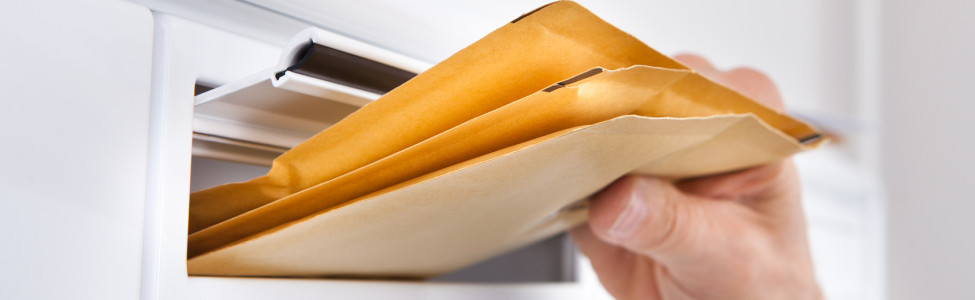 Close-up Of Postman Putting Letters In Mailbox